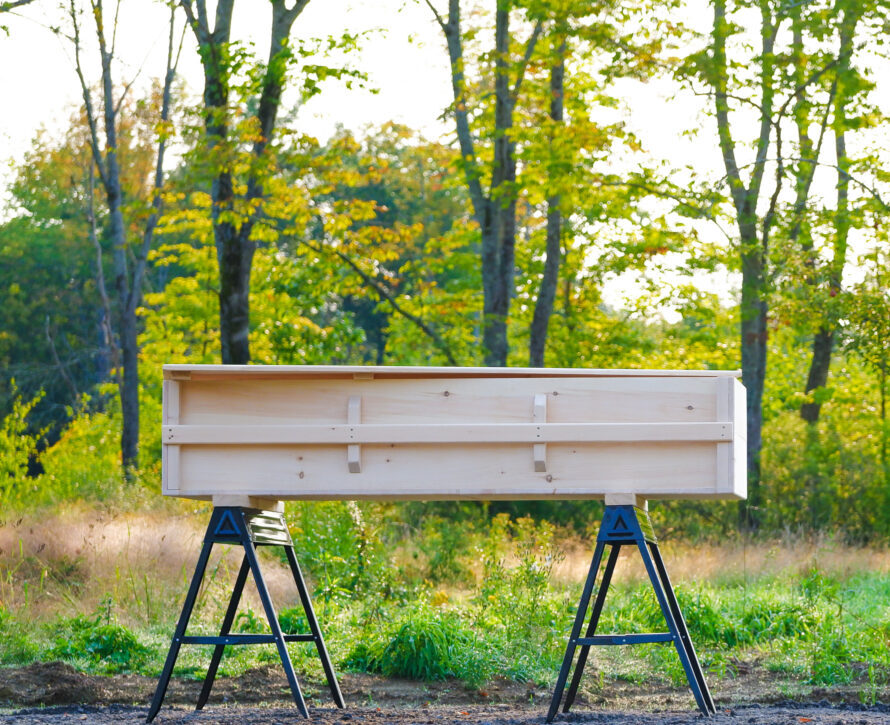 whole side view of finished casket showing hand rail. At distance on saw horses.