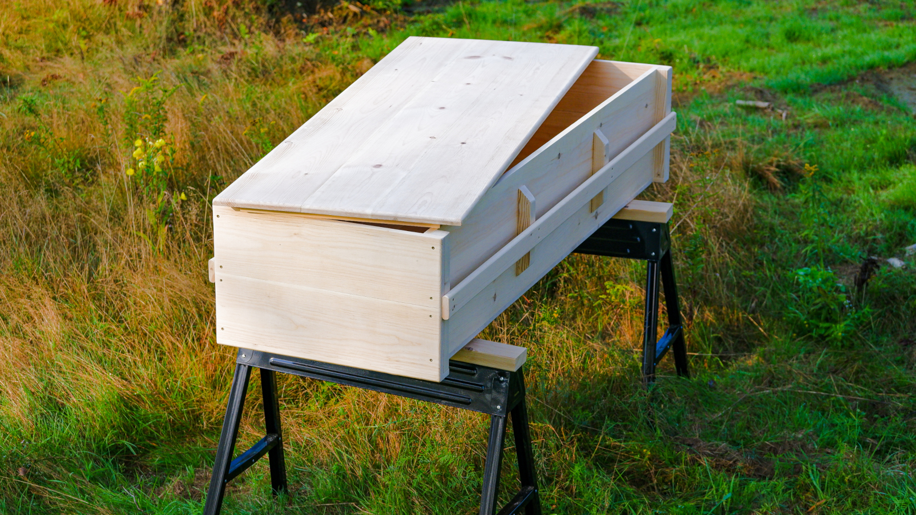 Casket whole view, top view partly open on saw horses.